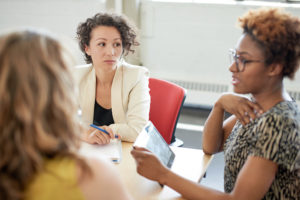 Photo of three female colleagues seated at a table having a meeting