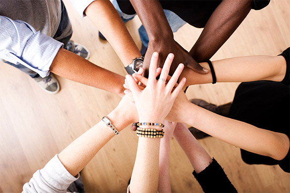 A birds eye view of five people standing in a circle with their hands together in the middle